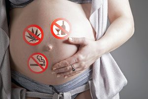 A pregnant woman with four different types of drugs on her belly.