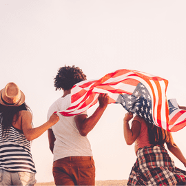 A group of people holding american flags on the beach.