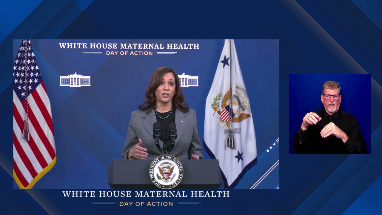A woman in front of an american flag and the white house maternal health logo.