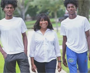 A woman standing between two young men in white shirts.