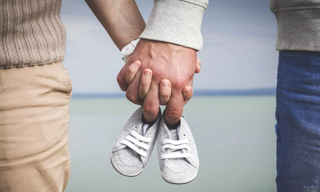 A couple holding hands while wearing white shoes.