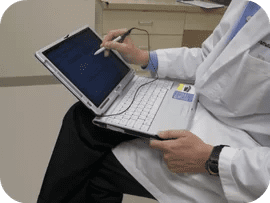 A doctor is sitting down and using his laptop.