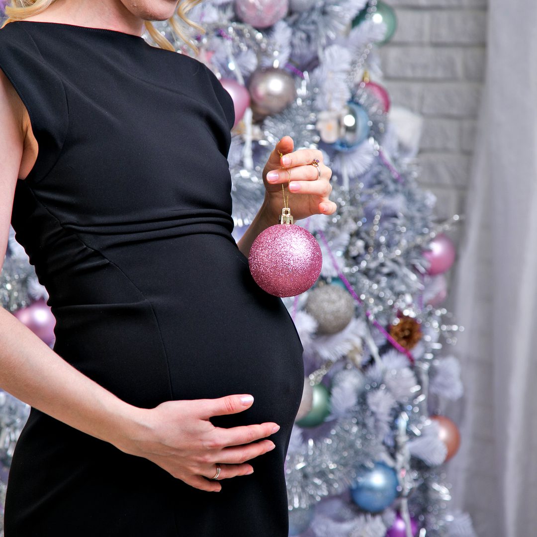 Pregnant holidays poster holding an ornament in pink color